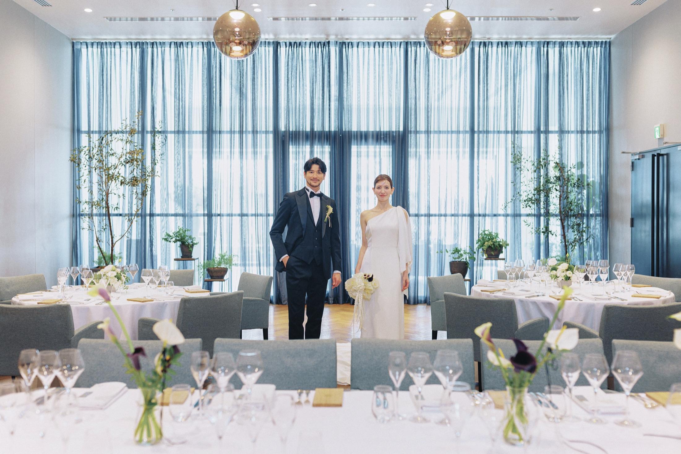 大開口の窓から光が入る会場に立つ新郎新婦